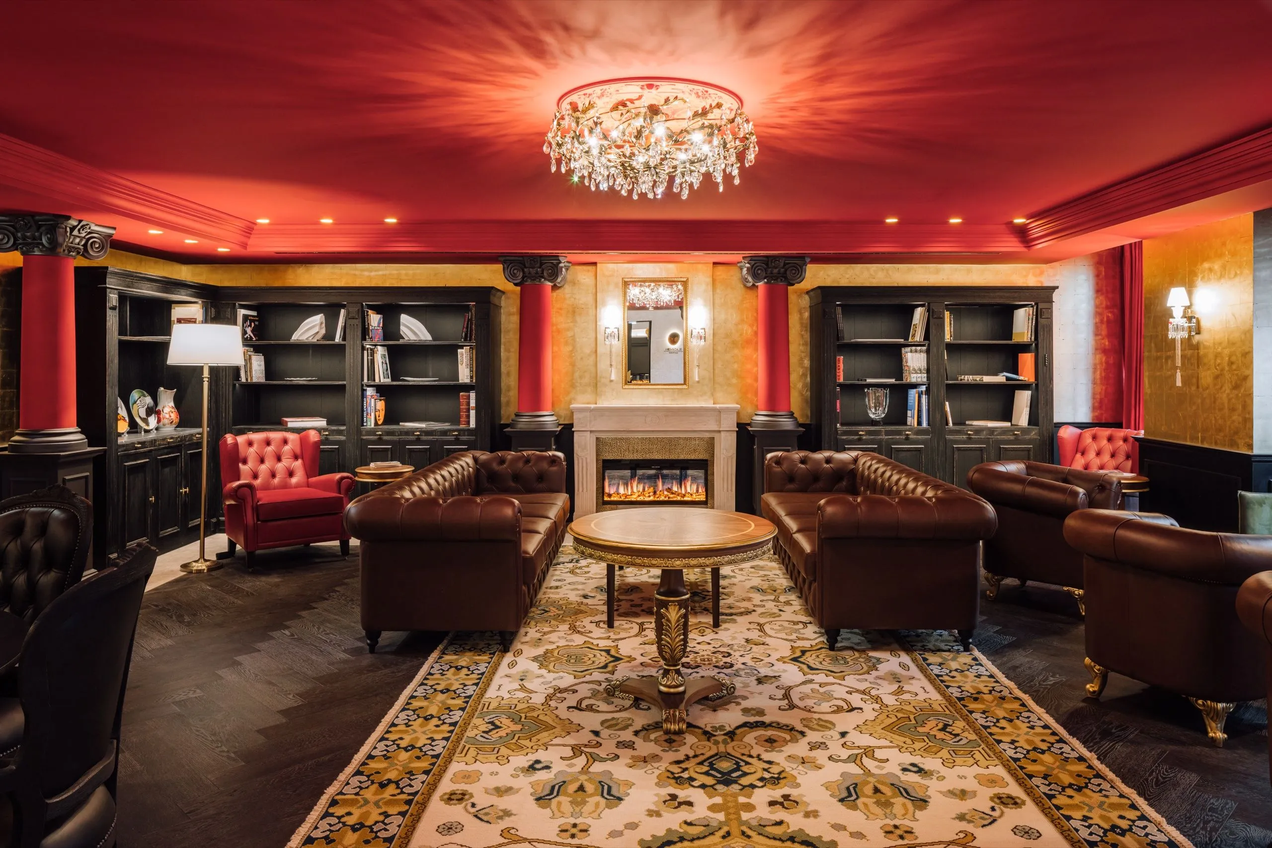 BLACK MOON Lounge mit roter Decke, Kronleuchter und Ledersofas.